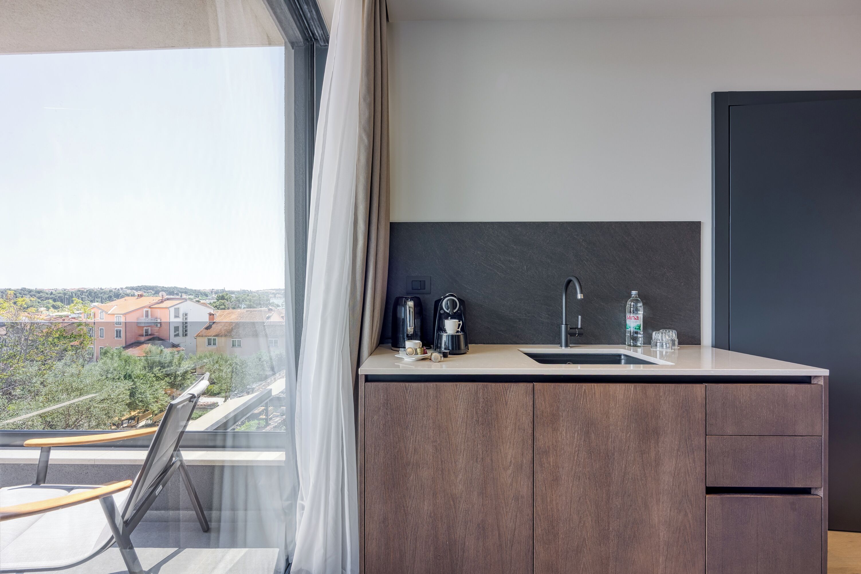 Eine moderne Küche mit einem großen Fenster, einer Kaffeemaschine, einem Spülbecken und einem Schrank.