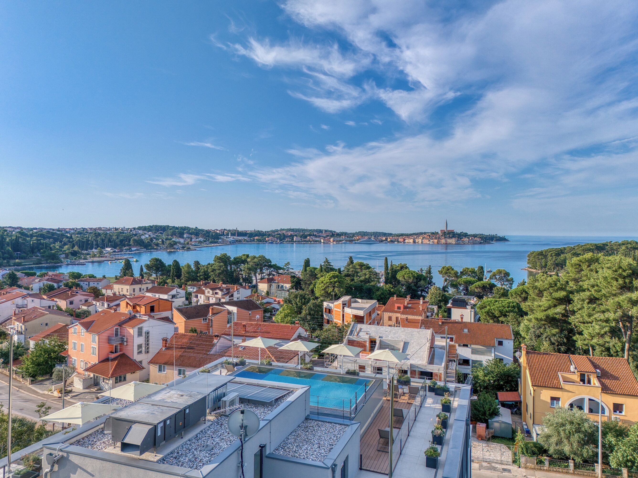 A coastal town with a clear view of the sea, residential buildings, and a prominent church tower.