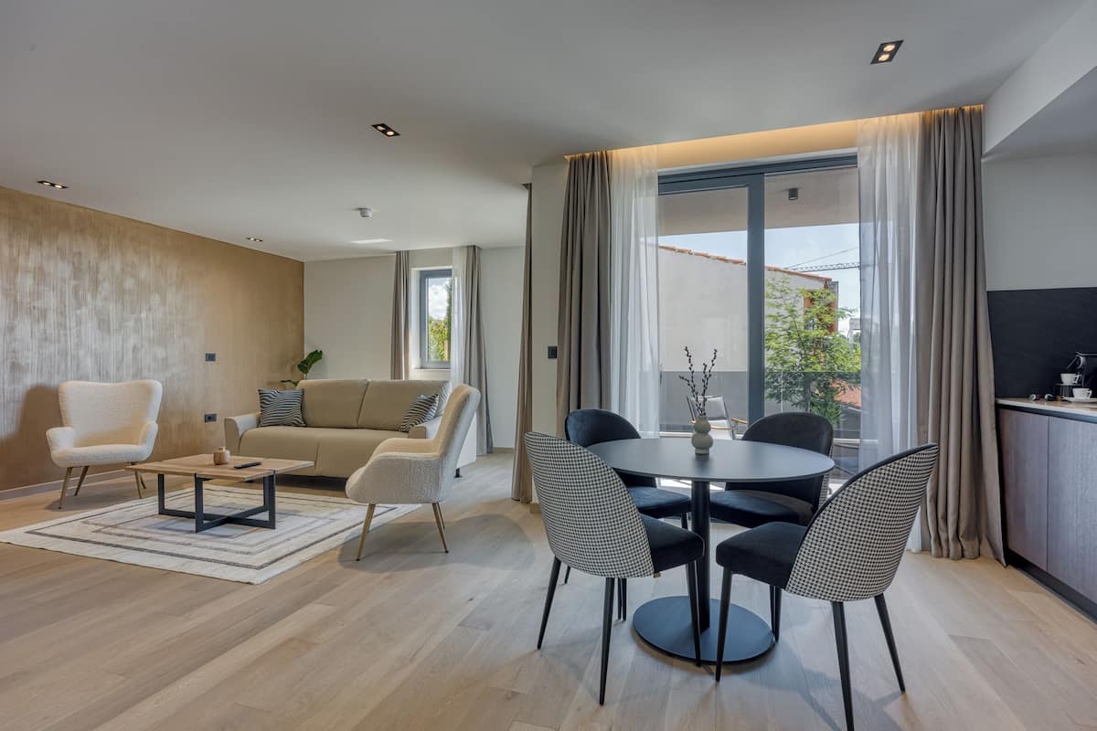 Ein modernes Wohnzimmer mit einer Couch, Sesseln, einem Couchtisch und einem Essbereich mit Stühlen und einem Tisch.