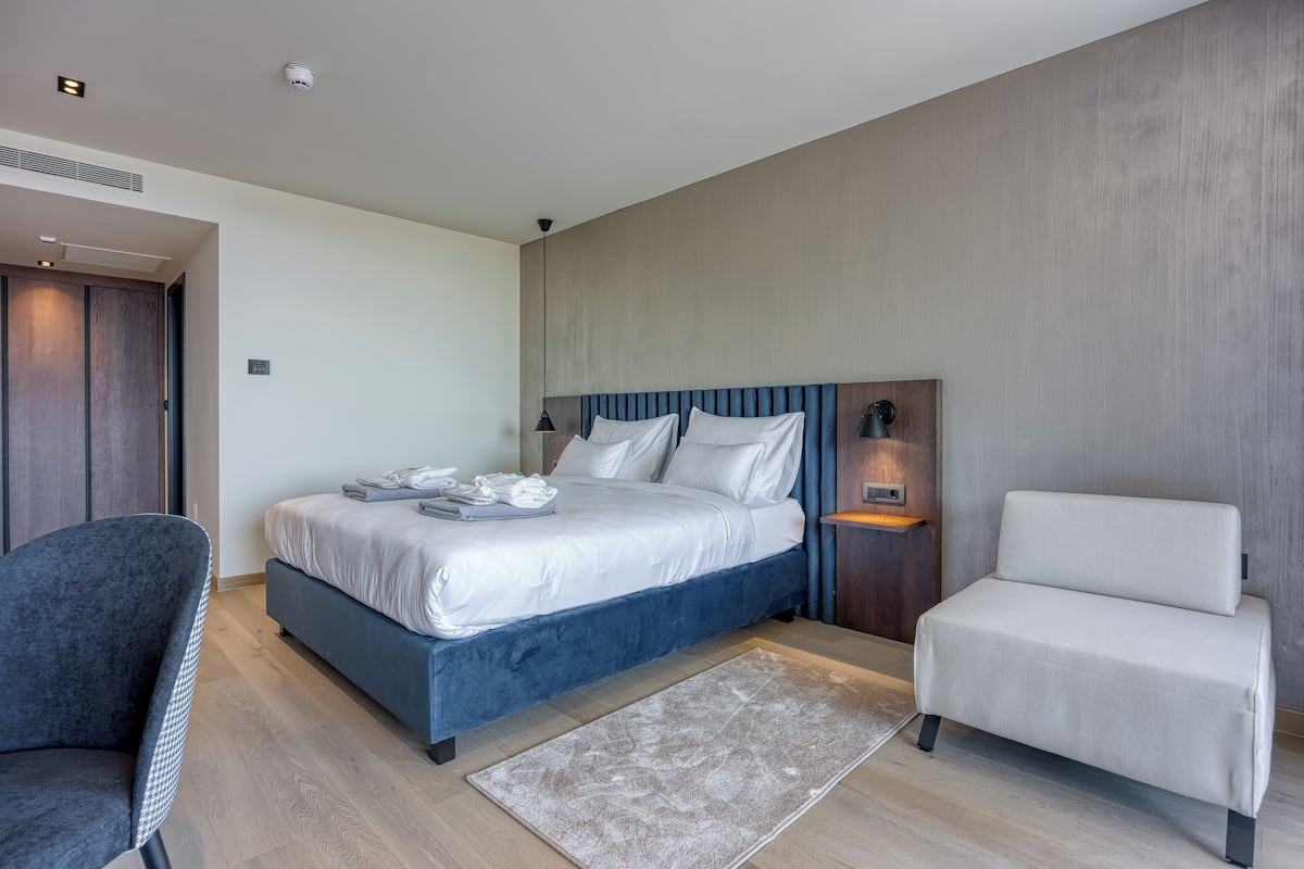 Ein modernes Hotelzimmer mit einem großen Bett, einer Sitzecke und einem kleinen Tisch mit einer Lampe.