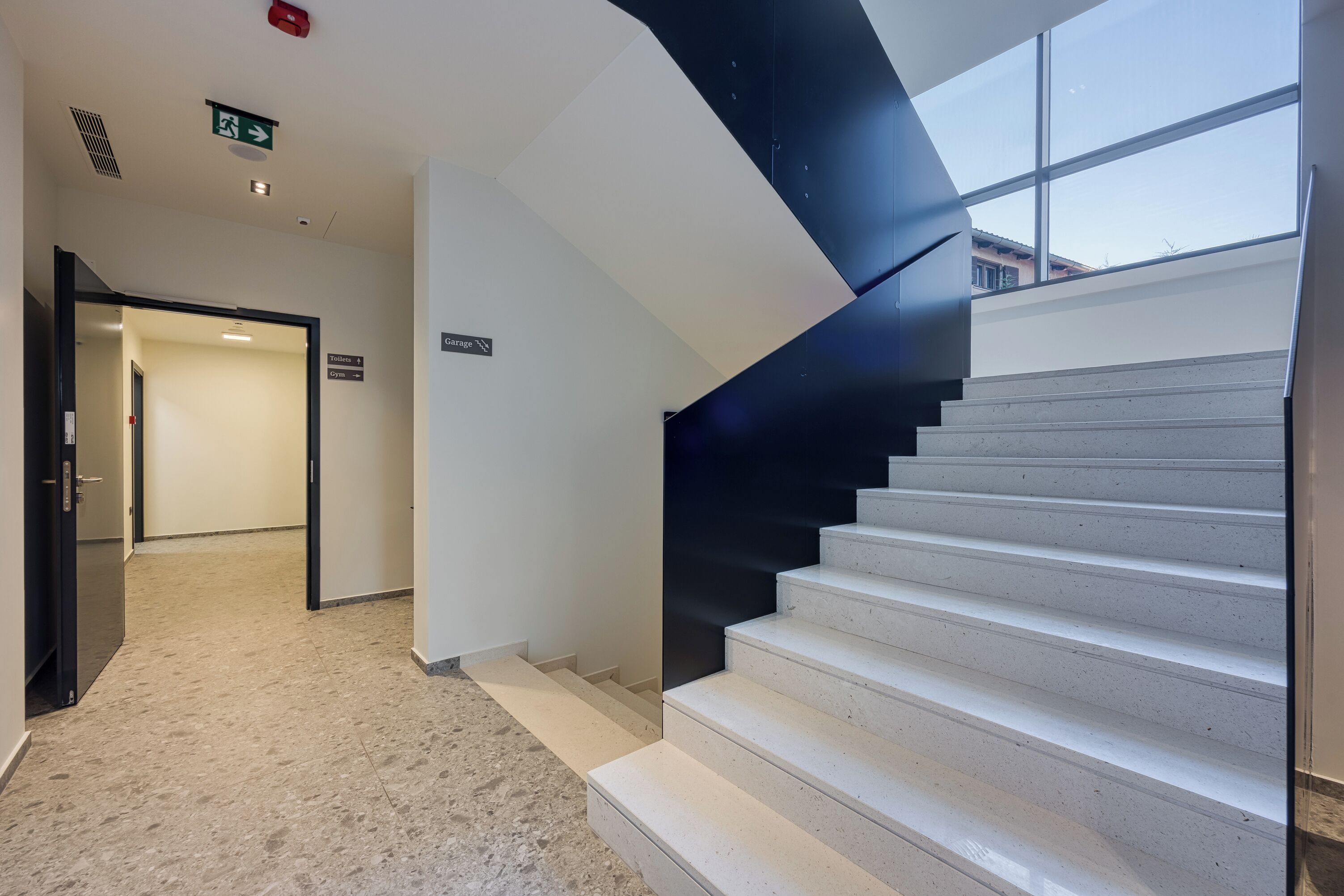 A modern staircase with a glass railing, leading to a second floor.