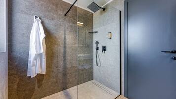 A modern bathroom with a glass shower enclosure, a towel rack, and a door.