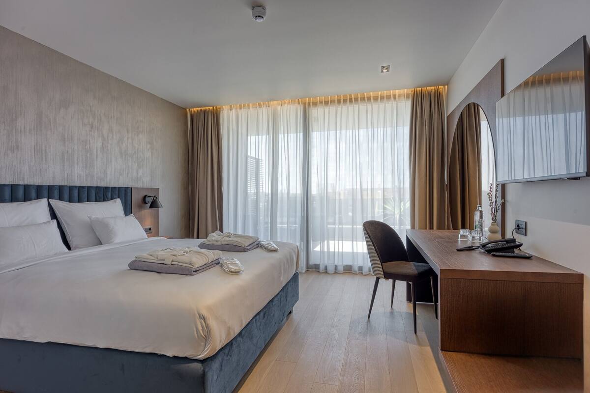Ein modernes Hotelzimmer mit einem großen Bett, einem Schreibtisch und einem Sessel.