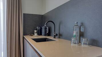 A modern kitchen with a sink, a kettle, and two glasses on the counter.