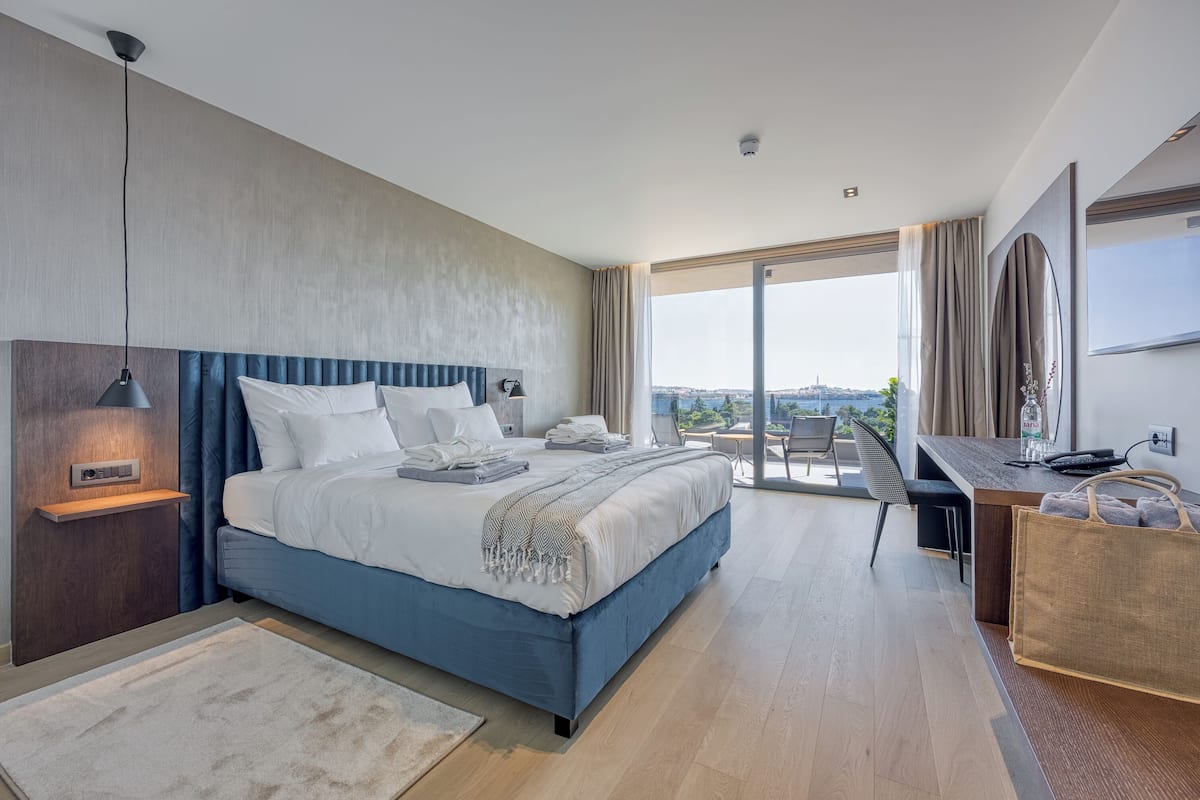 Ein modernes Hotelzimmer mit einem großen Bett, einem Schreibtisch und Blick auf die Stadt.