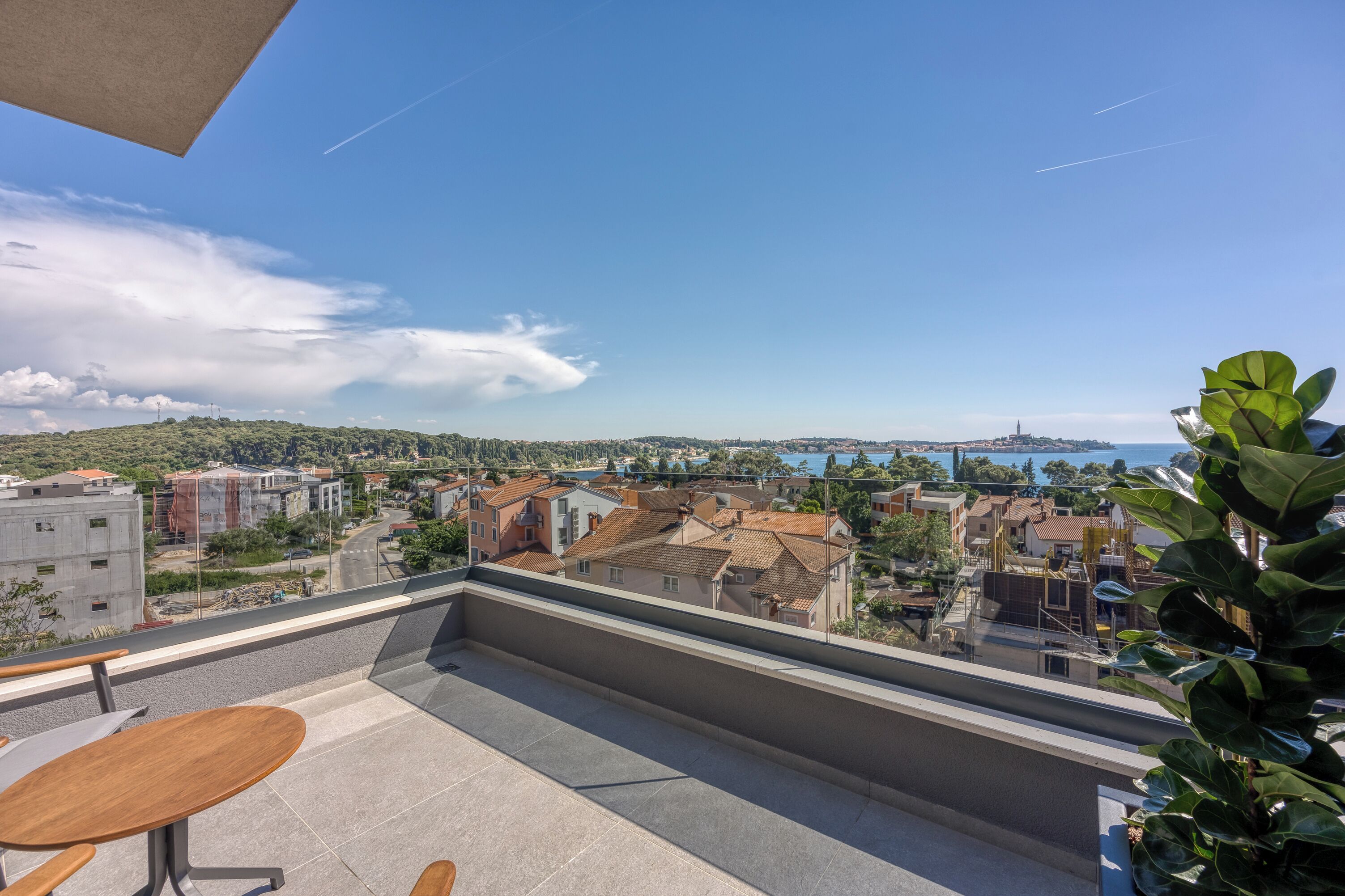 A balcony with a view of a town and a body of water.