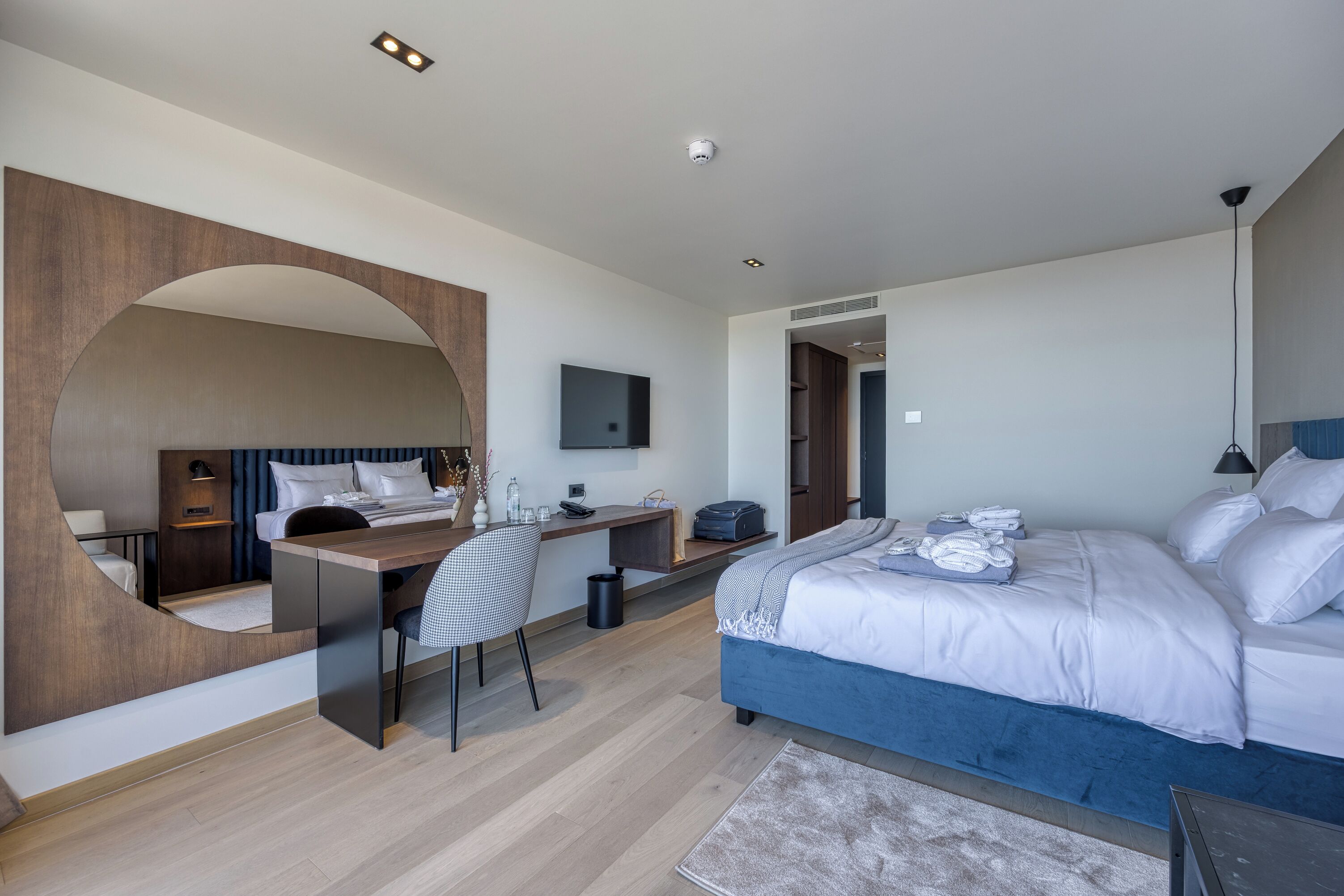 A modern hotel room with a large bed, a desk, and a TV.