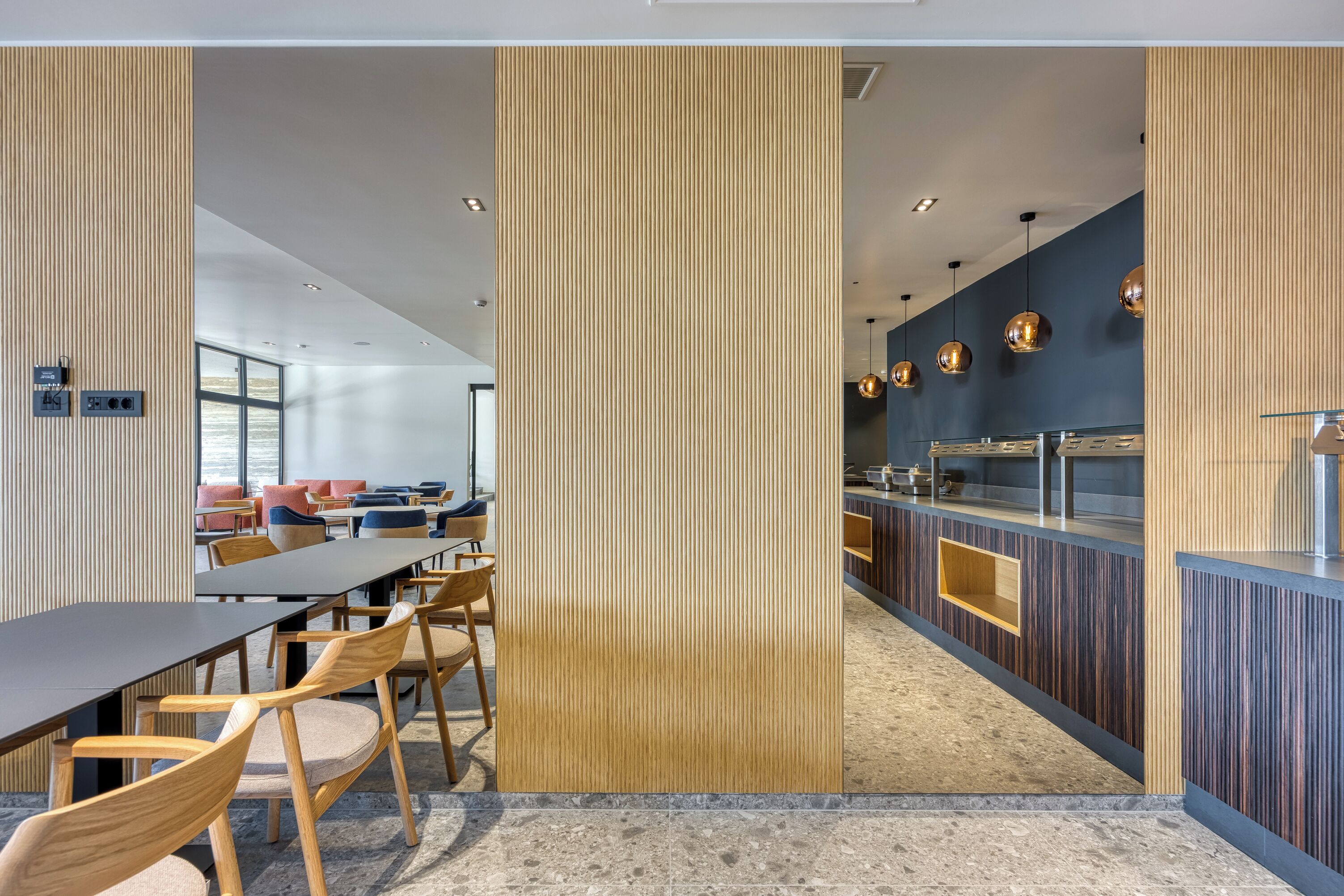 A modern dining area with a long table, chairs, and a counter with a sink.