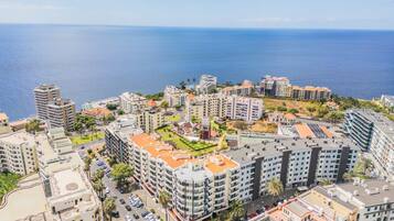 A coastal urban area with high-rise buildings, a marina, and a clear view of the sea.