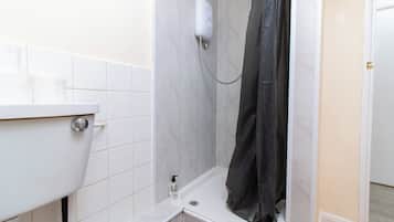 A bathroom with a white sink, a shower with a black curtain, and a white toilet.