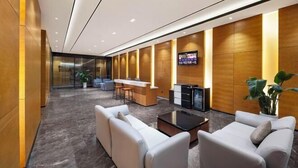 Un hall d’entrée moderne avec un comptoir d’accueil, un espace salon et un écran de télévision.