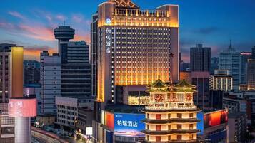 A modern hotel with a traditional pagoda-style structure in front, surrounded by high-rise buildings.