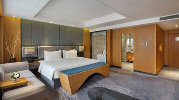 A hotel room with a large bed, a sofa, a desk, a mirror, and a wardrobe.