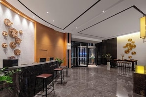 En modern hotellobby med en receptionsdisk, barstolar och en sittgrupp.