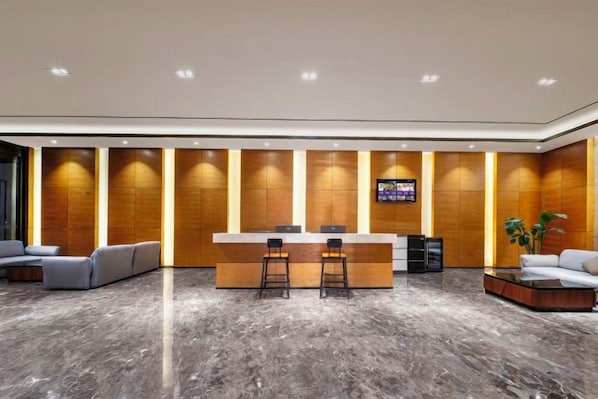 A modern reception area with a marble floor, wooden panel walls, a central counter with bar stools, and a flat-screen TV mounted on the wall. - Zhengzhou Bolui Hotel (Erqi Square David City) (Zhengzhou)