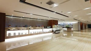 Un hall d’hôtel moderne avec un sol ciré, un comptoir d’accueil où sont exposés divers articles de confort, et un mur décoratif.