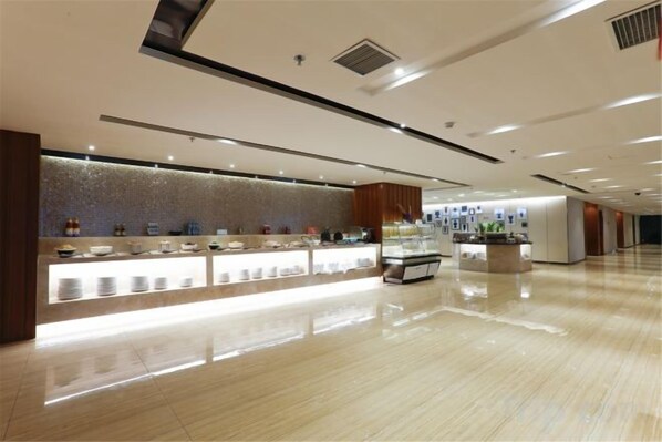 A modern hotel lobby with a reception desk, a food display, and a clean, polished floor.