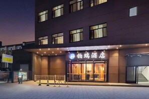 A hotel entrance with a sign, a gated entrance, and a paved area in front.