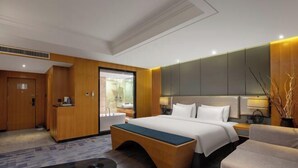 Una habitación de hotel moderna con una cama grande, un escritorio, un sofá y un baño visible a través de una puerta abierta.