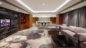Un salon moderne doté d’un téléviseur à écran plat, d’un canapé, d’une table basse et d’un coin repas avec des tables rondes.