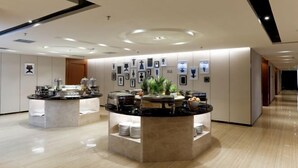 Un moderno vestíbulo de hotel con una barra de desayuno central, una pared decorada con obras enmarcadas y un piso limpio y pulido.