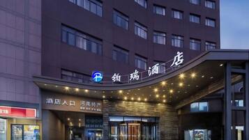 A hotel entrance with a modern design, featuring a prominent sign and a glass facade.