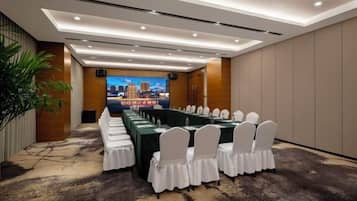 A conference room with a long table, white chairs, and a cityscape view.