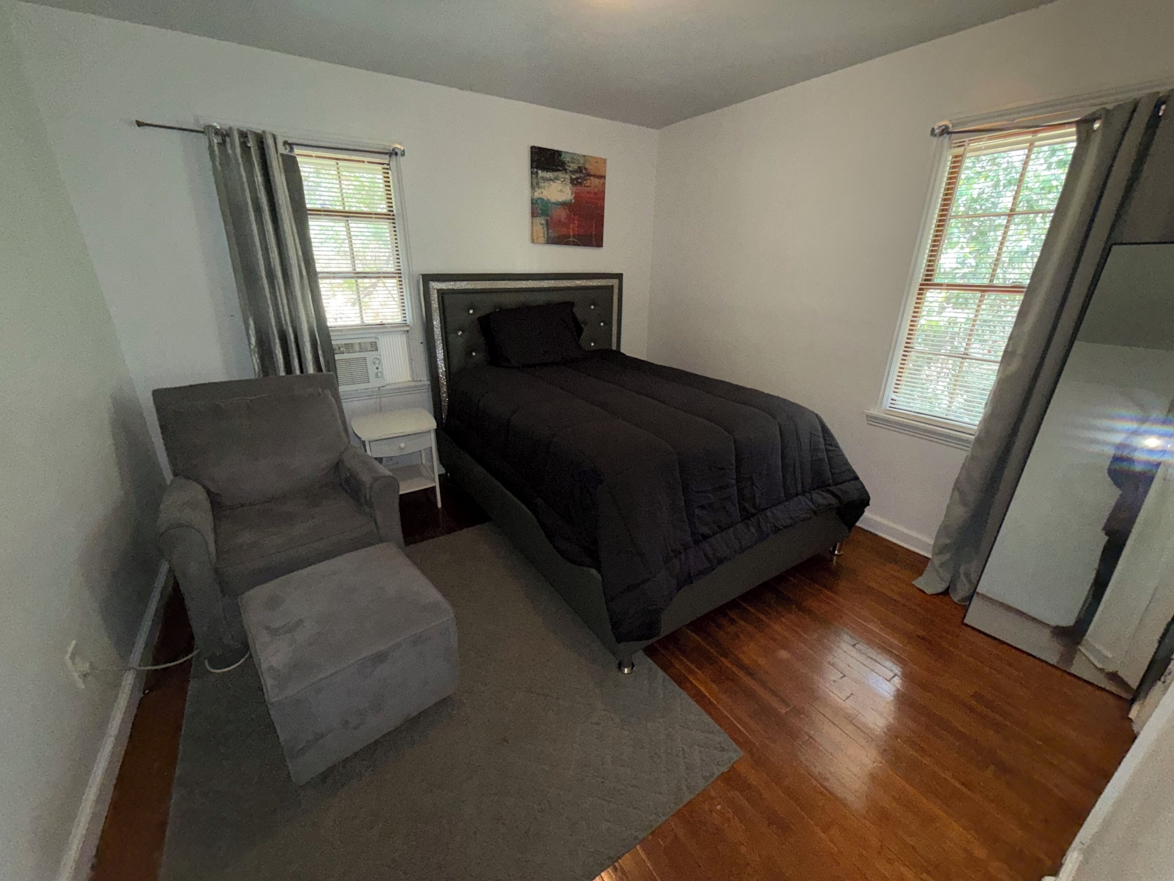 A bedroom with a bed, a chair, a small table, and a window.