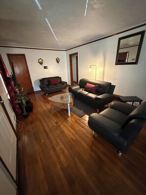A living room with a wooden floor, two sofas, a coffee table, and a mirror on the wall. - Home away from, Home! (Decatur)