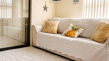 A living room with a sofa, decorative pillows, a starfish decoration, and a white rug.