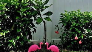 Un jardin avec un feuillage verdoyant et des statues de flamants roses.