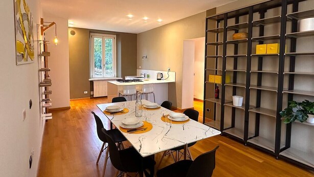 Un espace repas moderne avec une table en marbre, des chaises noires et une cuisine en arrière-plan.