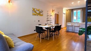 Un salon moderne avec un coin repas, un plancher en bois et une cuisine à l’arrière-plan.