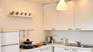 A modern kitchen with white cabinets, a stove, a sink, and a hanging light fixture. - Bergamo Center - Quarenghi House (Bergamo)