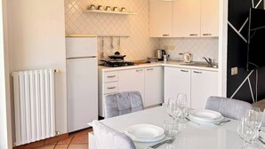 A modern kitchen with white cabinets, a dining table set for six, and a hanging light fixture. - Bergamo Center - Quarenghi House (Bergamo)