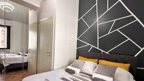 A bedroom with a bed, a mirror, and a geometric-patterned wall. - Bergamo Center - Quarenghi House (Bergamo)