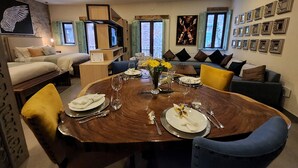 A dining area with a wooden table set for four, surrounded by sofas and chairs.