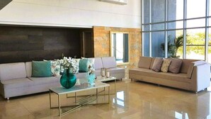 A modern living room with a beige sofa, a glass coffee table, and a large window providing natural light. - PONY PALACE Best Rooftop Pool in Cartagena! Beachfront, 3BR luxury condo balcony (Unknown)
