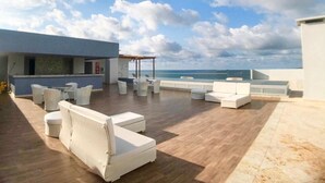 A rooftop terrace with white outdoor furniture, a bar area, and a view of the sea. - PONY PALACE Best Rooftop Pool in Cartagena! Beachfront, 3BR luxury condo balcony (Unknown)