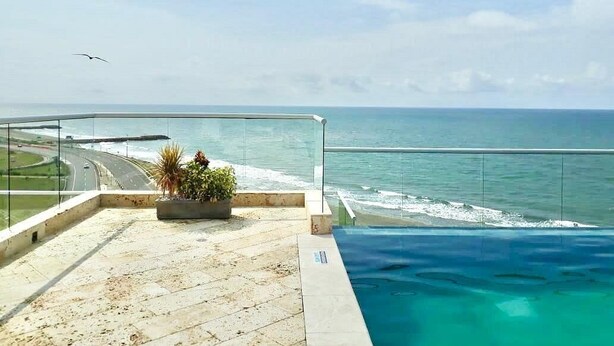 A rooftop pool with a view of the ocean and a road. - PONY PALACE Best Rooftop Pool in Cartagena! Beachfront, 3BR luxury condo balcony (Unknown)
