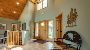 A spacious room with a high ceiling, wooden beams, and a large window. - New! Epic Lake Views, Games, Hot Tub Comfort & A/C (Oakland)