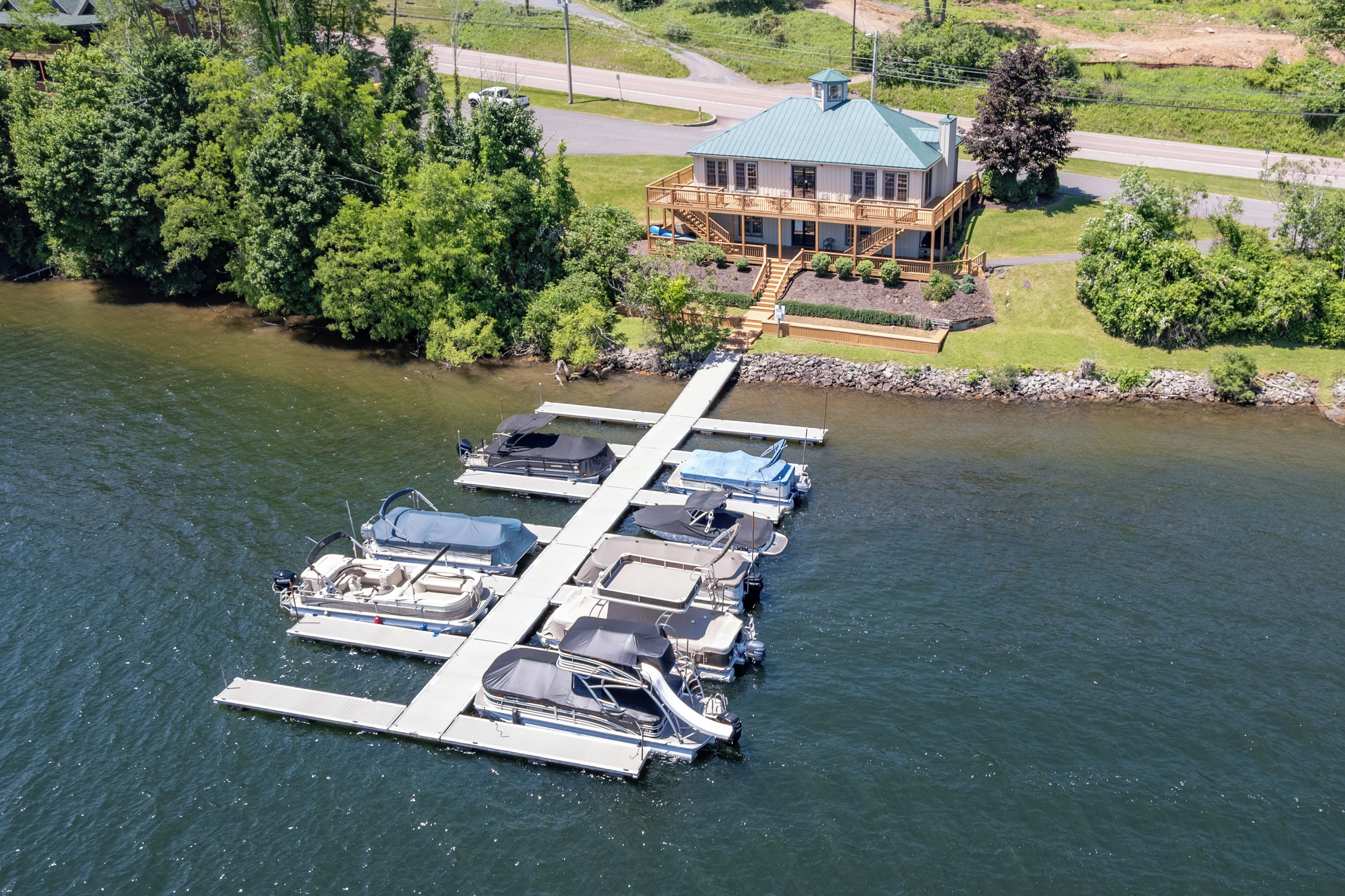 A marina with boats docked, a house with a blue roof, and a dock extending into the water.