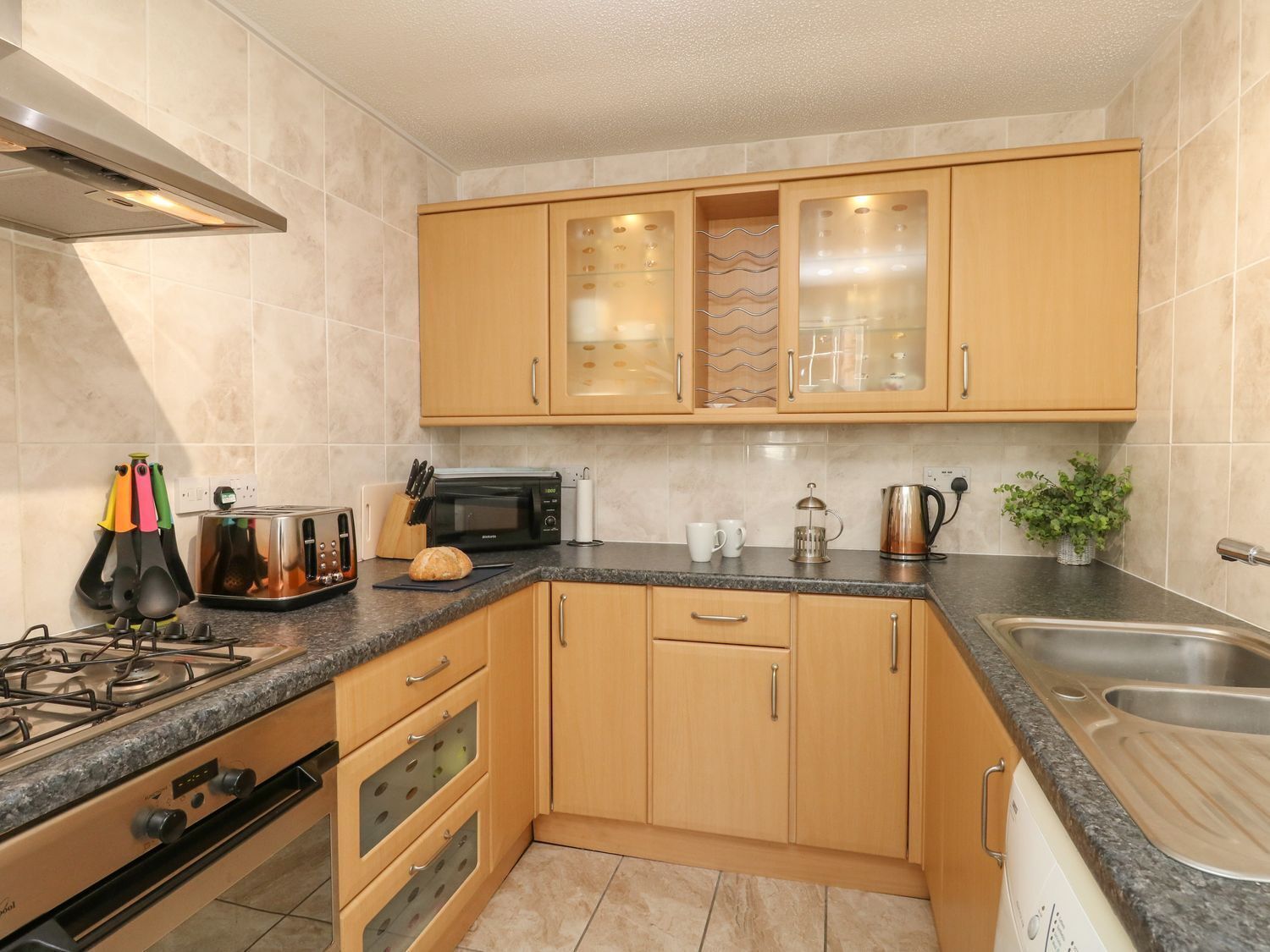 A compact kitchen with wooden cabinets, a built-in microwave, a gas stove, and a stainless steel sink.