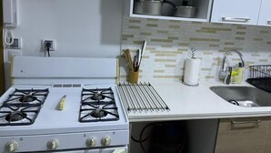 A kitchen with a white stove, a sink, and cabinets above the countertop.