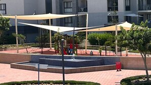 A courtyard with a fountain, shaded seating areas, and a playground.