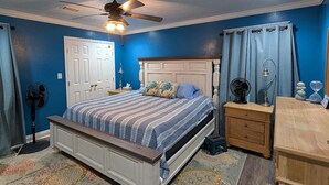 A bedroom with a bed, a ceiling fan, a nightstand, a dresser, and a rug. - 4 min walk Ocean View Sleeps 14.  Pet Ramp. Fenced Yard. King Bed 75" TV (Bolivar Peninsula)