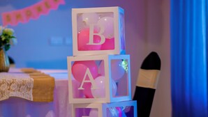 Una pila de bloques con letras formando la palabra 'BABY' y un adorno de globo rosa.
