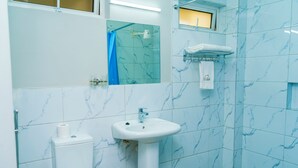 Un baño con inodoro, lavamanos y zona de ducha.