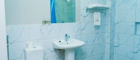 Ein Badezimmer mit Toilette, Waschbecken und Duschbereich.