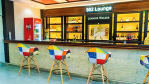 Una zona de bar con un refrigerador de Coca-Cola, un letrero de 902 Lounge y una exhibición de Johnnie Walker.